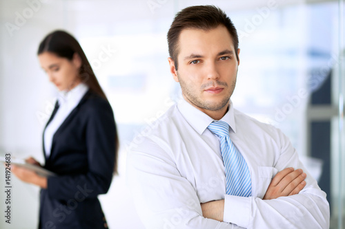 Smiling businessman in office with colleagues in the background