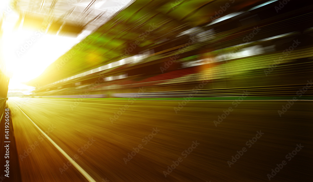 Foward motion speed lens blur racing circuit background with seated stand , sunset scene . Foward motion speed lens blur racing circuit background with seated stand , sunset scene .