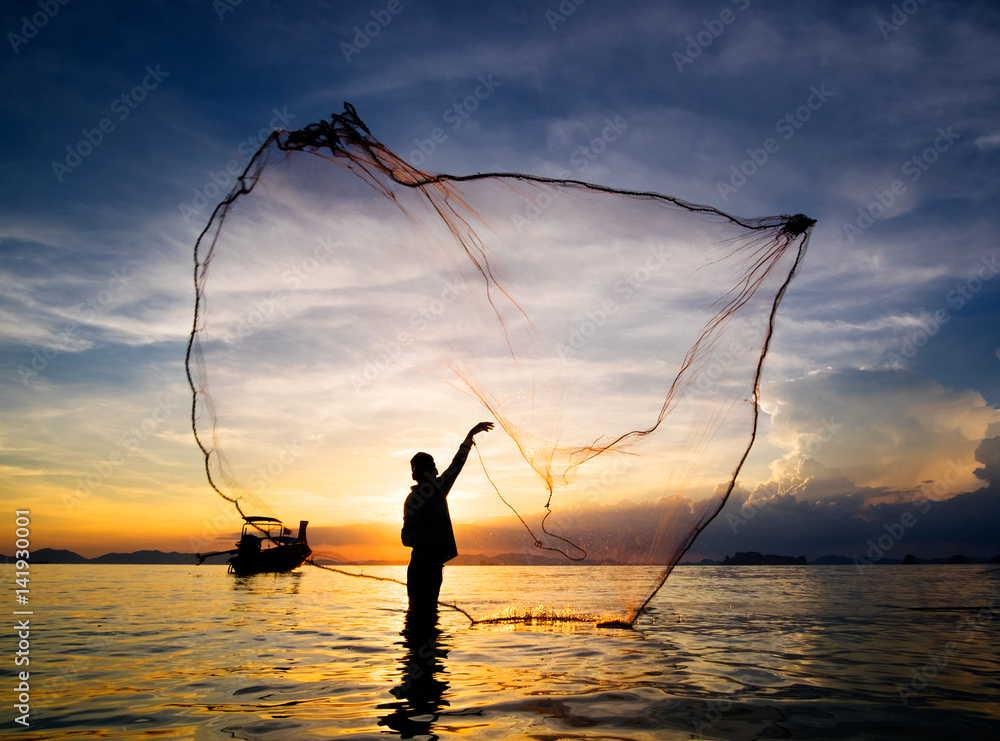 Hunting for Sunset. Silhouette of fisherman throwing fishing net into the sea, Thailand.