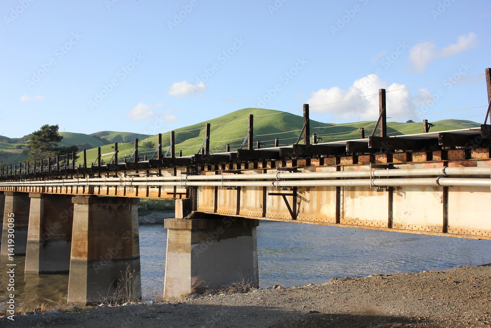 Train bridge over water with green hills