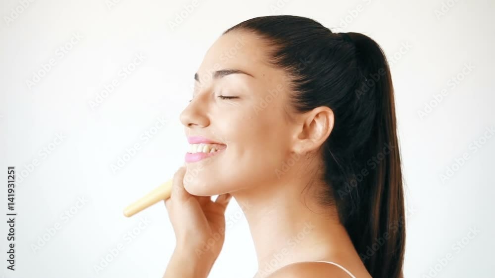 Profile of smiling young woman applying powder on her face Profile of smiling young woman applying powder on her face