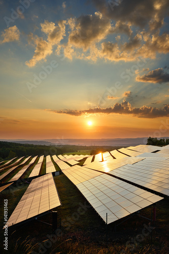 Sunset over photovoltaic panels of solar power station in the countryside. View from above.