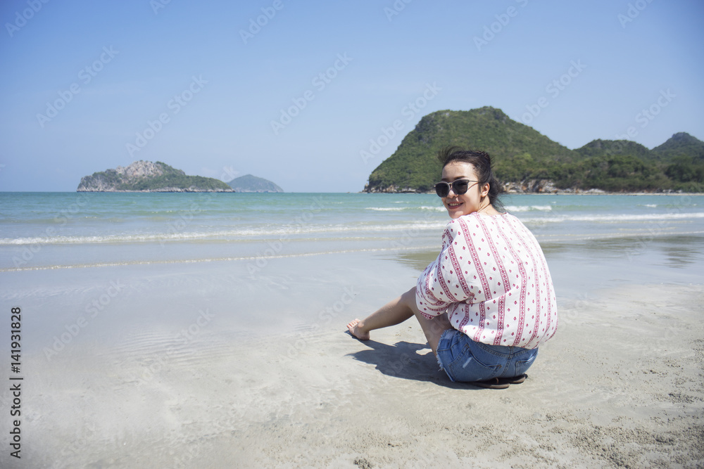 Asian teenager woman has take a relaxing on beautiful beach. Wearing sunglasses and holding a camera. Siam Smiling girl. rest time at the beach with big mountain. Filtered image. Selective focus Asian teenager woman has take a relaxing on beautiful beach. Wearing sunglasses and holding a camera. Siam Smiling girl. rest time at the beach with big mountain. Filtered image. Selective focus