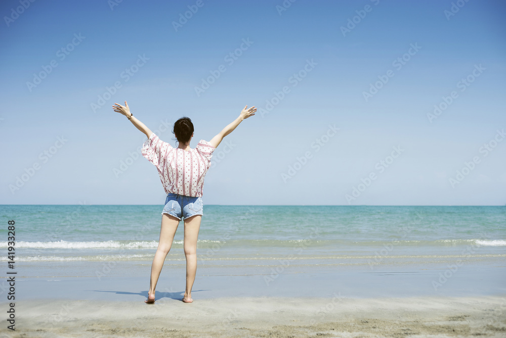 Asian teenager woman has take a relaxing on beautiful beach. Rising up her hand about freshen or happy concept. happy girl. rest time at the beach. Filtered image. Selective focus Asian teenager woman has take a relaxing on beautiful beach. Rising up her hand about freshen or happy concept. happy girl. rest time at the beach. Filtered image. Selective focus