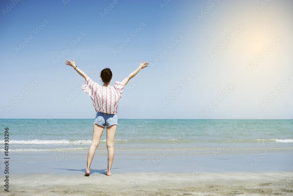Asian teenager woman has take a relaxing on beautiful beach. Rising up her hand about freshen or happy concept. happy girl. rest time at the beach. Filtered image. Selective focus Asian teenager woman has take a relaxing on beautiful beach. Rising up her hand about freshen or happy concept. happy girl. rest time at the beach. Filtered image. Selective focus