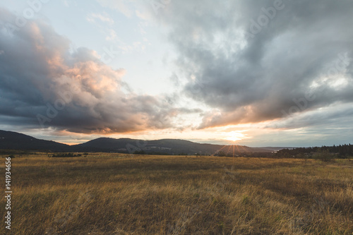 Cloudy Sunset Over Mountains and Field