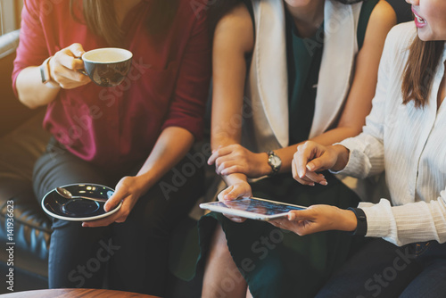 Close up scene of 3 woman using tablet together in coffee shop photo