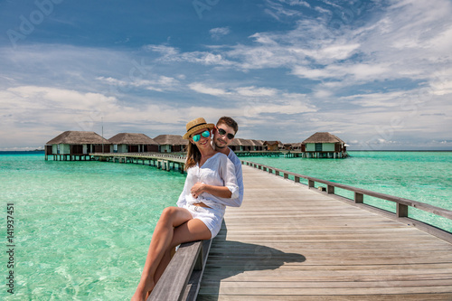 Couple in white on a beach jetty at Maldives © haveseen