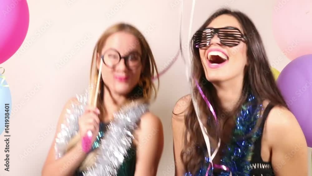 Two beautiful women having fun dancing using props in party photo booth Two beautiful women having fun dancing using props in party photo booth