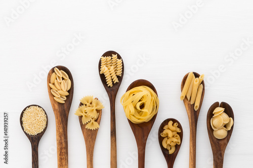 Pasta selection of penne, gnocci, rigatoni, casarecce, fiorelli, pasta Farfalle, pasta A Riso, Orecchiette Pugliesi, Gnocco Sardo and Farfalle in wooden spoons over white background