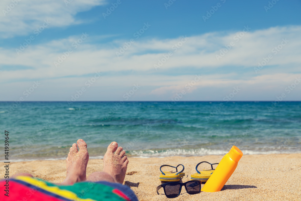 Man sunbathing on the sandy beach. Shallow depth of field on feet and flip flops. Man sunbathing on the sandy beach. Shallow depth of field on feet and flip flops.