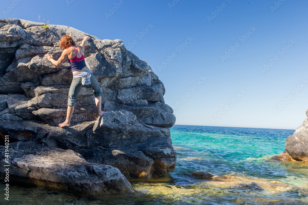 Beautiful woman boudering rock climbing on the shore