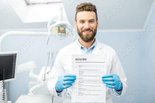 Professional dentist holding resume for a new job standing at the dental office