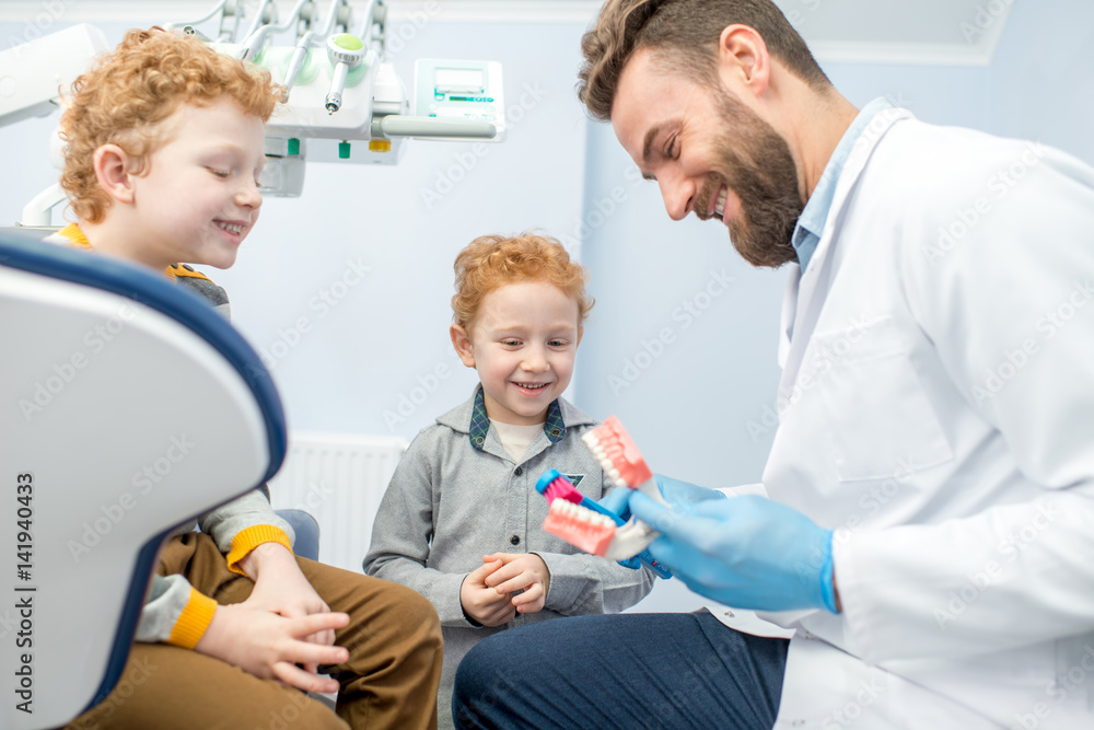 Children's dentist showing the boys how to brush teeth on artificial jaw at the dental office Children's dentist showing the boys how to brush teeth on artificial jaw at the dental office