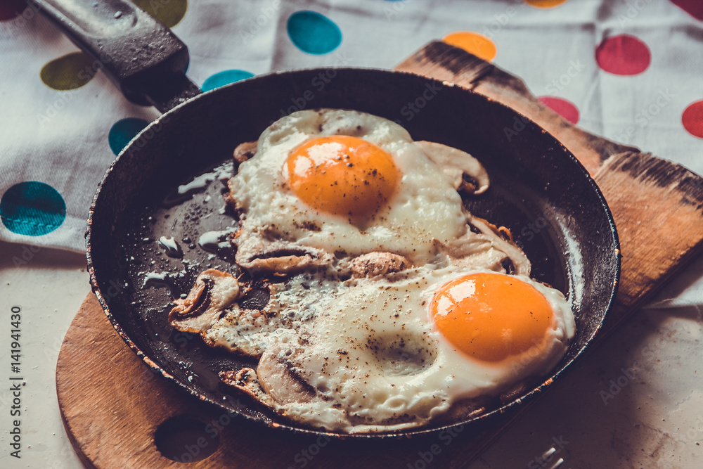 Two fried eggs with mushrooms in a pan Two fried eggs with mushrooms in a pan