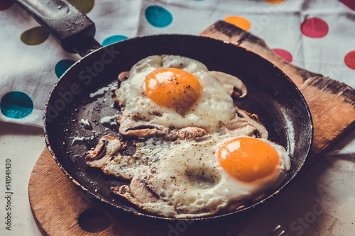 Two fried eggs with mushrooms in a pan