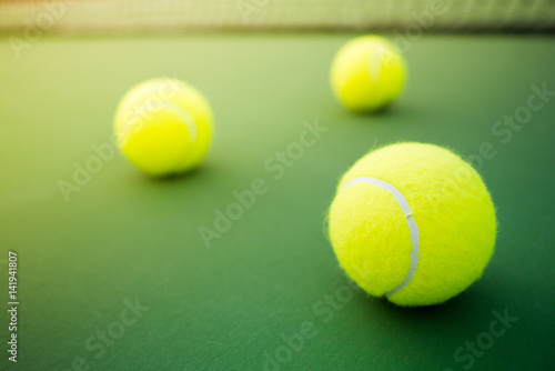 three tennis balls on green and red hard court © angyim