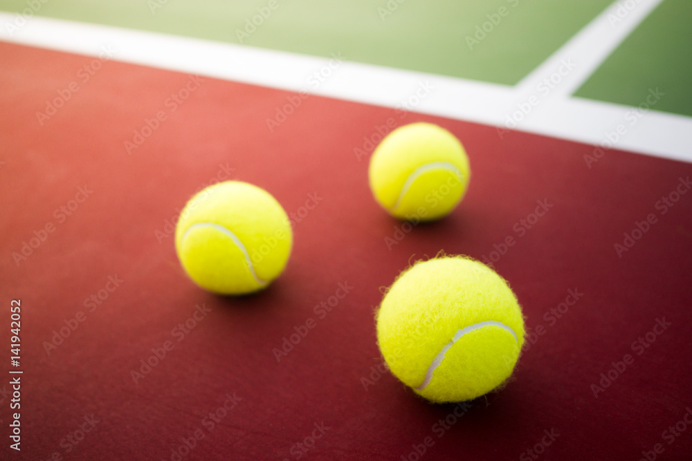 three tennis balls on green and red hard court