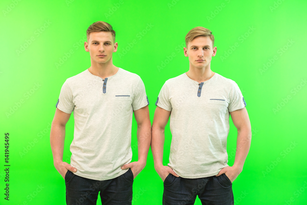 The two twin brother stand on the green background The two twin brother stand on the green background