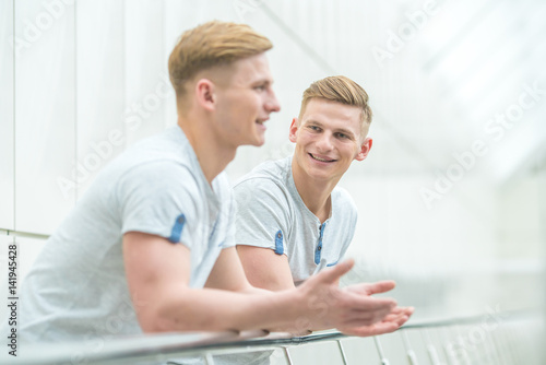 The two smile brother stand on the office balcony and gesture © realstock1