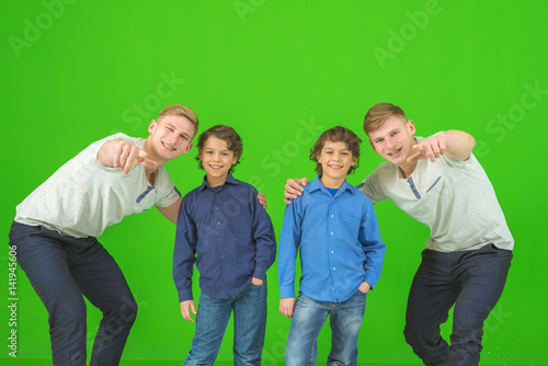 The four happy brothers stand on the green background and gesture