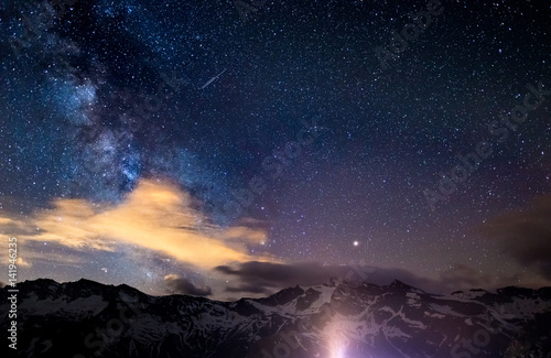 The colorful glowing core of the Milky Way and the starry sky captured at high altitude in summertime on the Italian Alps  Torino Province. Mars and Saturn glowing mid frame.