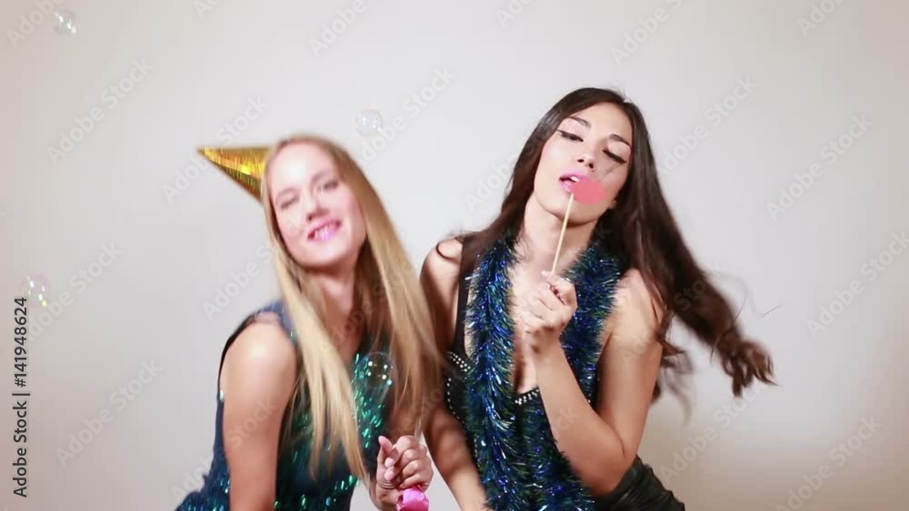 Two attractive girls dancing and sending kisses in party photo booth Two attractive girls dancing and sending kisses in party photo booth