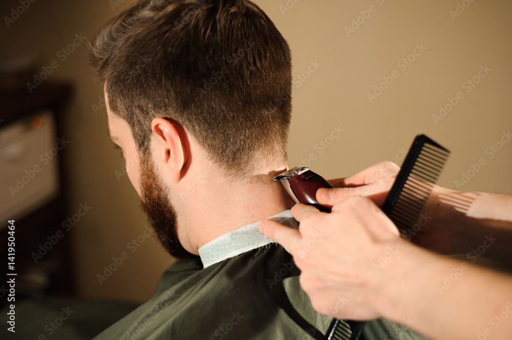 Master cuts hair and beard of men in the barbershop Master cuts hair and beard of men in the barbershop