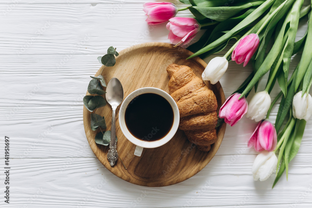 Cup of coffee with croissant and fresh tulips on wooden background for Mother's Day. Cup of coffee with croissant and fresh tulips on wooden background for Mother's Day.