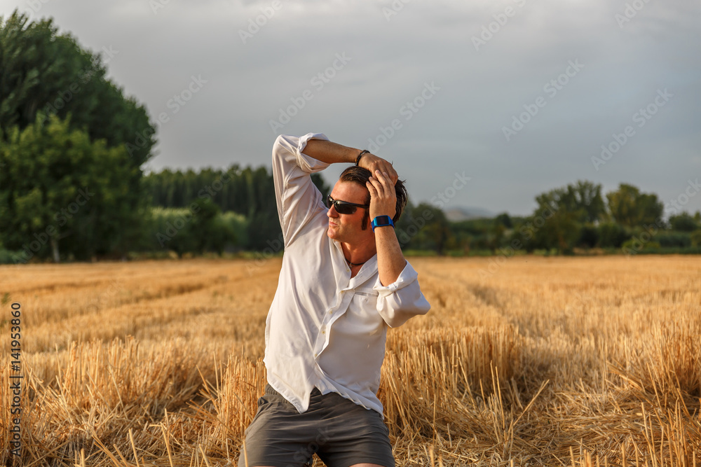 Attractive man collects his long hair while he is in the middle of a harvest Attractive man collects his long hair while he is in the middle of a harvest