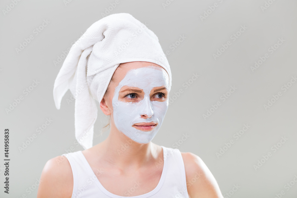 Portrait of young woman with facial mask on gray background. Portrait of young woman with facial mask on gray background.