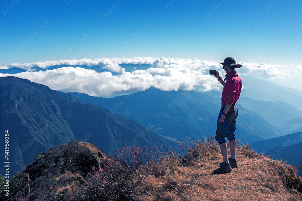 Hiker enjoying Mountain Scenery staying on high Rock
