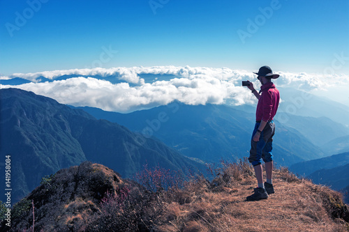 Hiker enjoying Mountain Scenery staying on high Rock
