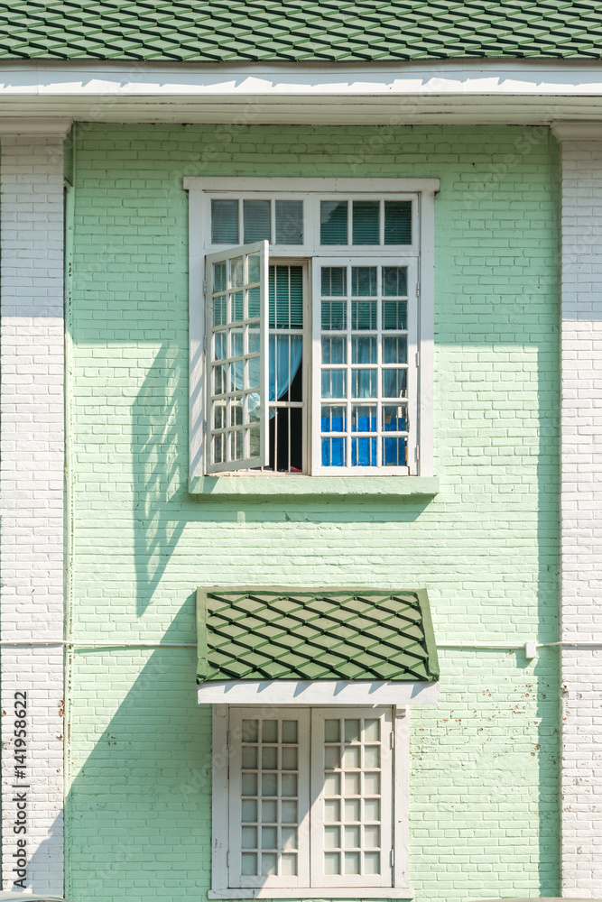 Antique white frame wooden window with beautiful light and shadow the old green brick wall retro style Antique white frame wooden window with beautiful light and shadow the old green brick wall retro style