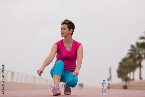 Young woman tying shoelaces on sneakers