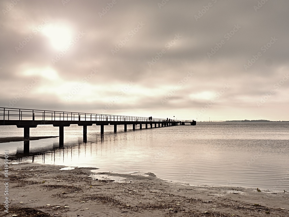 Long wooden pier at coast, cold morning, peaceful silent day