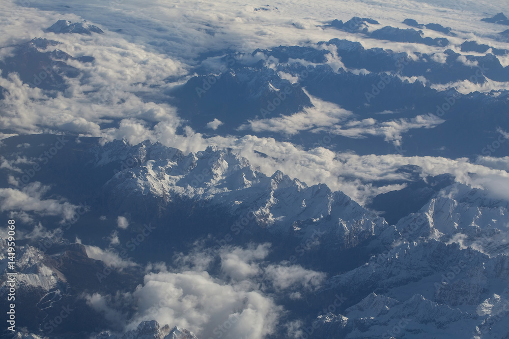 Idyllic snowy mountain peaks under clouds from plane Idyllic snowy mountain peaks under clouds from plane