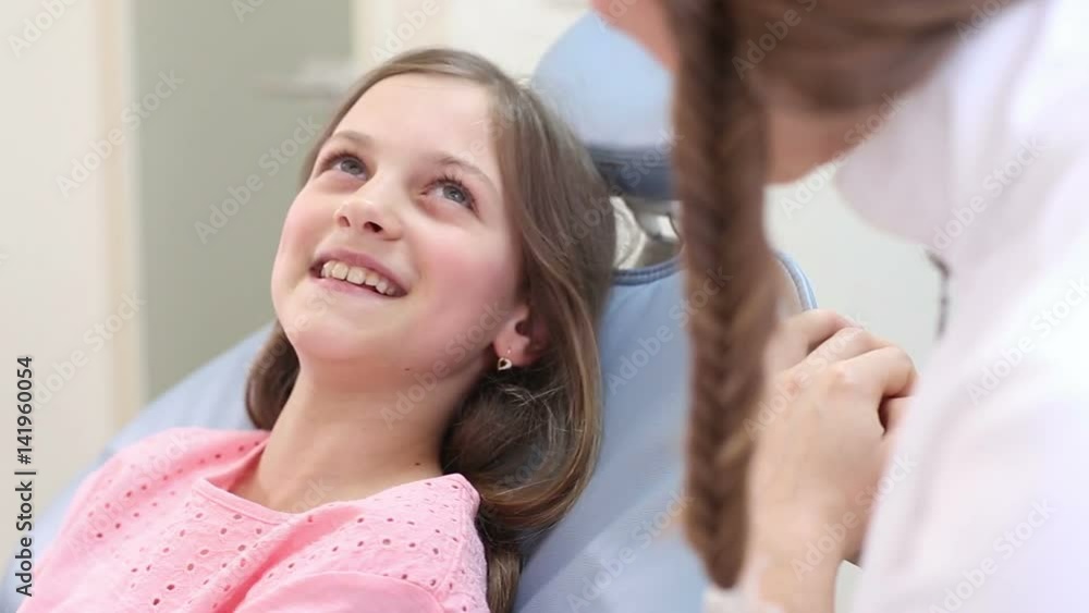 Close up of cute little girl sitting in the dental chair talking with female dentist Close up of cute little girl sitting in the dental chair talking with female dentist
