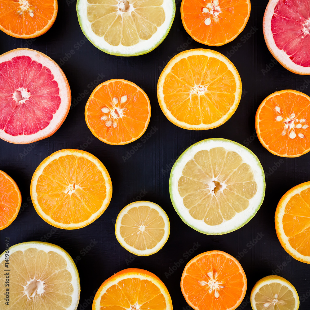 Fototapeta premium Lemon, orange, mandarin and grapefruit on black background. Flat lay, top view. Fruit colorful background