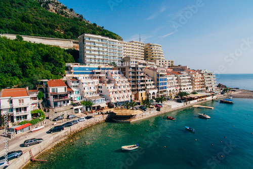 Settlement Rafailovici, Budva Riviera, Montenegro. The coast of the city on the Adriatic Sea. Aerial photography. Boats at sea, hotels, villas and apartments on the coast.