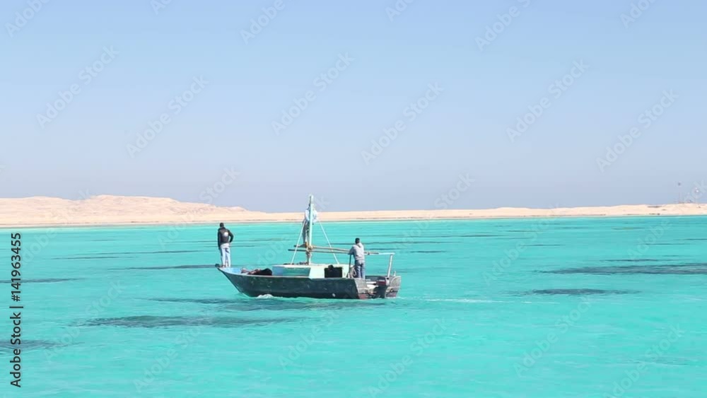 HURGHADA, EGYPT - FEBRUARY 13, 2016: Local people driving wooden boat on the Red sea. HURGHADA, EGYPT - FEBRUARY 13, 2016: Local people driving wooden boat on the Red sea.