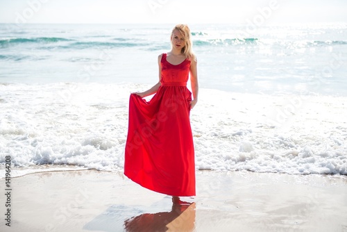 Beautiful blonde woman with red dress in the beach