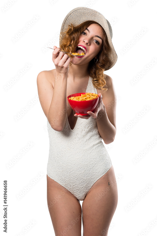 Pretty young model woman in swimsuit eating cereals from a bowl Pretty young model woman in swimsuit eating cereals from a bowl