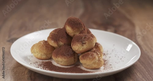 profiteroles with cocoa powder pan reveal on table, 4k prores footage