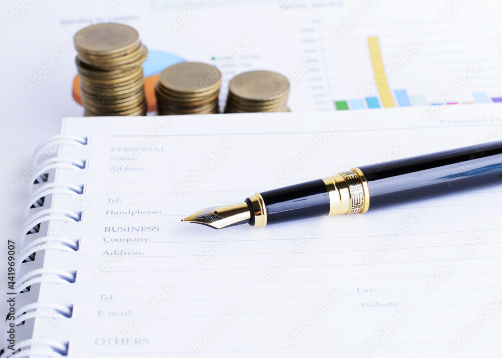 Business Fountain pen and Coins stack on document report Business Fountain pen and Coins stack on document report