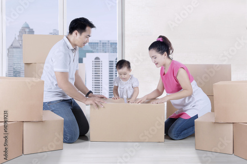 Young parents packing cardboard with their daughter