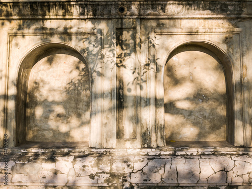 Slika na platnu Old wall with stone alcove and recess with sunlight in buddhist temple, wall bac