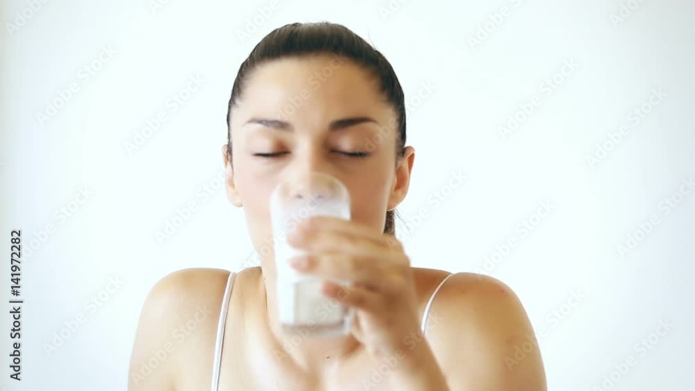 Close up portrait of attractive brunette woman drinking glass of milk on isolated white background Close up portrait of attractive brunette woman drinking glass of milk on isolated white background