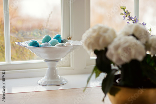 Stone or marble eggs in white stand next to a window. photo