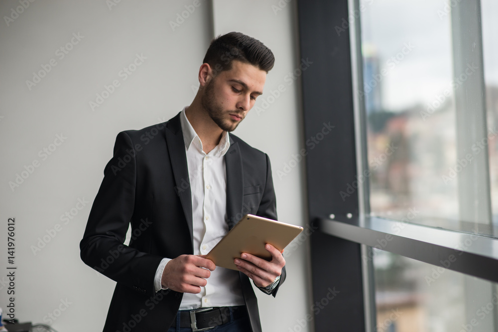 Young guy in an office looking at his tablet